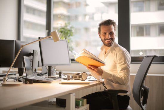 man sitting at desk with laptop smiling